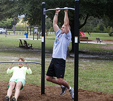 Man and Woman working out on Chin Up bars at an Outdoor Fitness Park