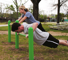 Man and Woman working out on a Push-Up Bar at Outdoor Fitness Park